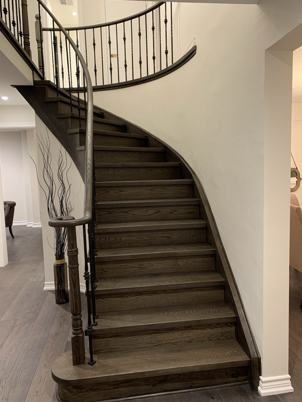 Curved staircase after renovation, stained hardwood and wrought-iron railing
