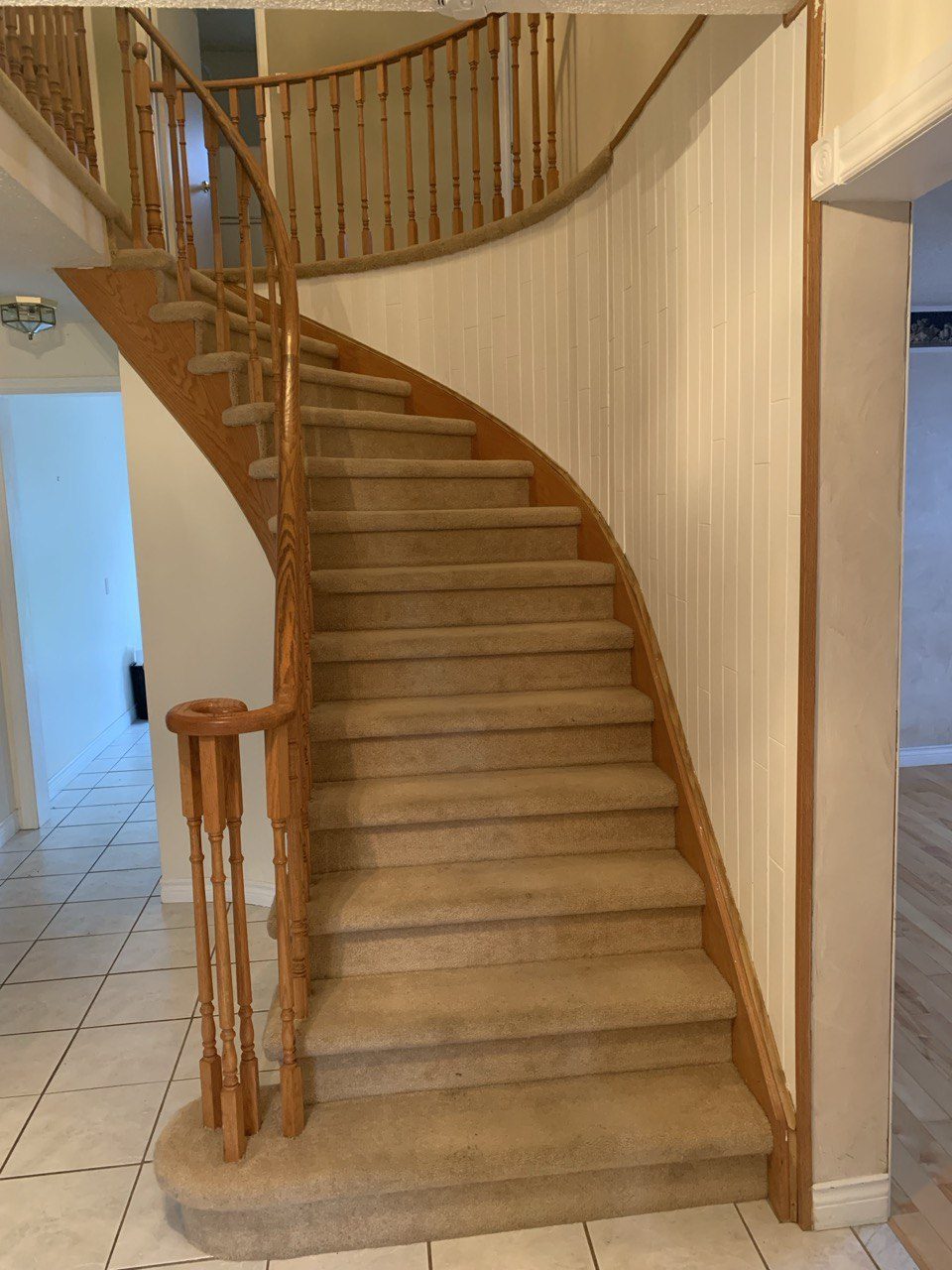 Curved staircase before renovation, worn carpet and oak spindles