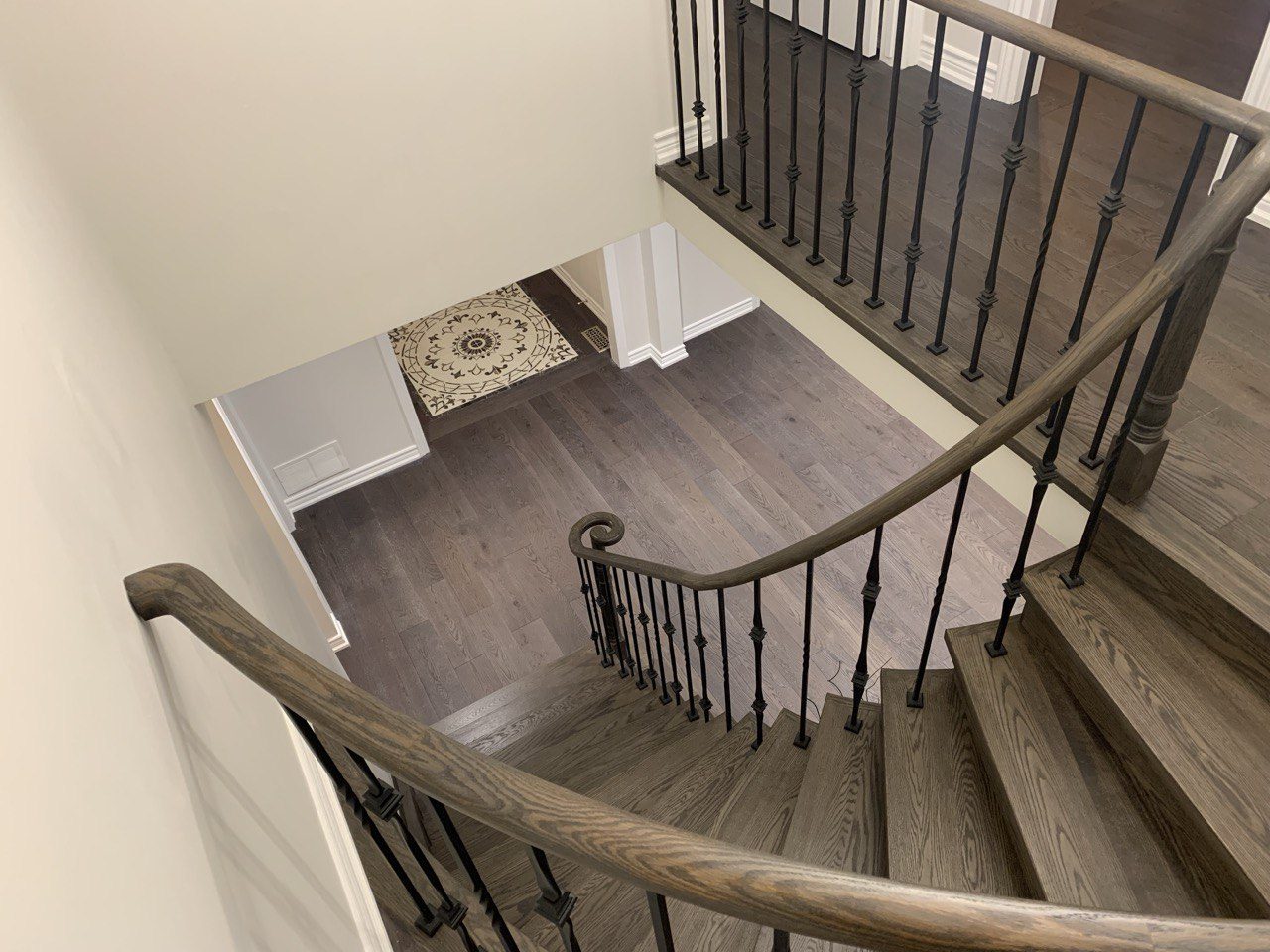 Staircase after renovation, stained hardwood treads with wrought-iron spindles
